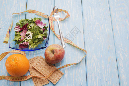 新鲜的绿色蔬菜叶子沙拉木制餐桌亮橙色和面包以及健康饮食的概图片