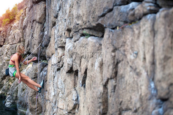 登山者靠在路线上并在绳索上称重这个女孩正在从事运动攀岩登山者攀登岩图片