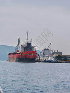 一艘大型红船油轮停靠在码头上拖船图片