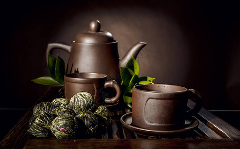 棕色背景中粘土茶壶和杯子的静物图片