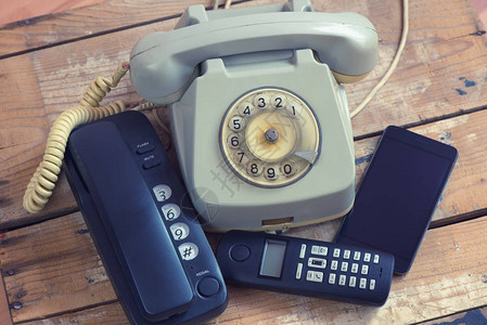 不同类型的电话固定电话智能手机木板上图片