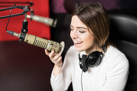 无线电台年轻女电台主持人用耳机和麦克风对青年图片