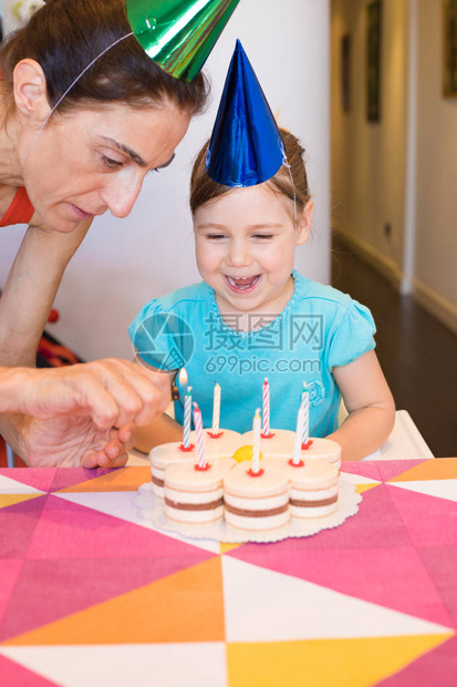女人用打火机在家里的彩色桌布上点着生日蛋糕上的蜡烛图片