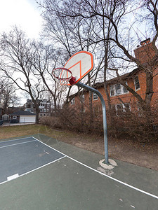 城市室外篮球场和白色和橙色篮板篮筐和网安装在金属柱上的照片图片