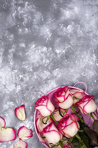 红玫瑰花束和粉红色礼物盒放在石桌上图片