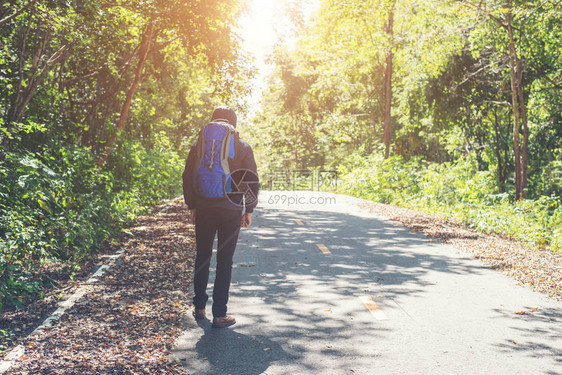 度假时在农村公路上行走的远足男子的后座图片