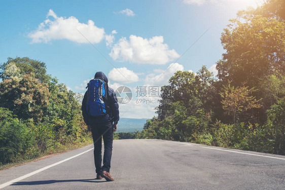 度假时在农村公路上行走的远足男子的后座图片