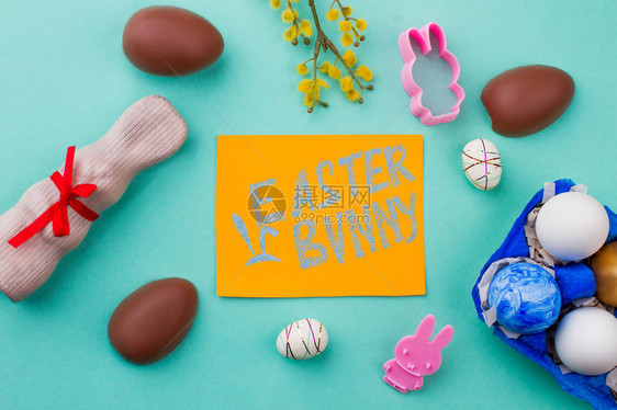 带有文本复活节兔子的卡片复活节糖果鸡蛋巧克力兔子和彩色背景上的褪色柳祝图片