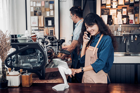 亚洲咖啡师服务员使用平板电脑在咖啡店接受顾客的订单图片