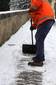 环卫工人扫落叶工人在冬季下雪后从冰冻的背景