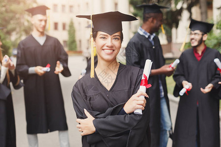 年轻的微笑女人在大学毕业那天与多民族的人站在一起教育资图片