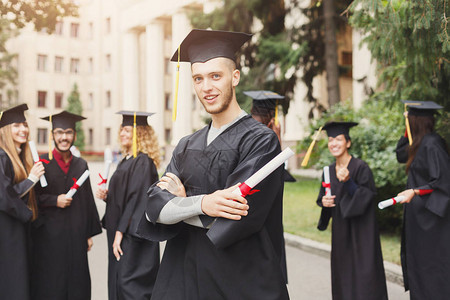 年轻的微笑男在大学毕业那天与多民族的人站在一起教育资图片