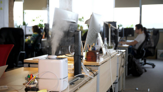 在办公室工作的年轻人的背景下工作的加湿器办公室里健康的工作环境加湿图片