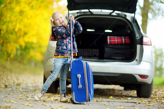 可爱的女孩带着手提箱准备和她的父母去度假孩子公路旅行或旅行学校的秋假带图片