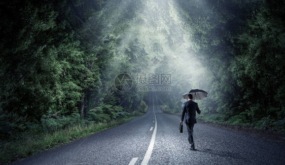 有黑色雨伞的商人在沥青路上行走光图片