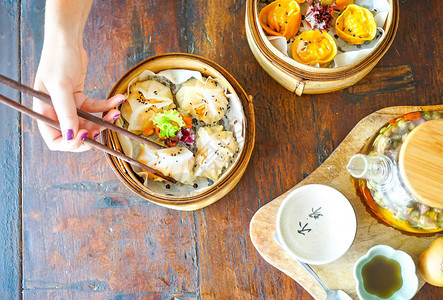 虾无麸质饺子咖喱鸡蒸饺有筷子的手拿着一块在一家餐馆的木桌背景传统的菜带复制空图片