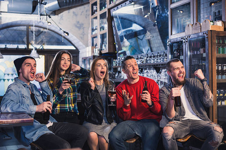啤酒龙虾胜利小组年轻漂亮的朋友在酒吧休息时看电视并为他们的团队欢呼支持你背景