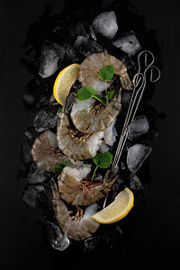 深黑板厨房餐盘和餐巾纸上加柠檬和柠檬的新鲜大虾图片