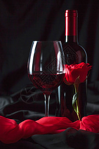 酒瓶和一杯红葡萄酒红色丝绸和红玫图片