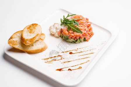 鞑靼配鲑鱼和黄瓜配面包丁的白盘图片