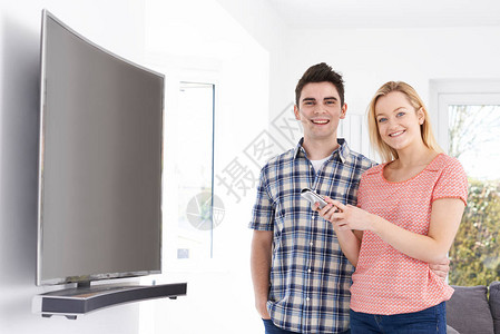 家中新曲线电视屏幕电视年轻夫妇与新弯曲图片