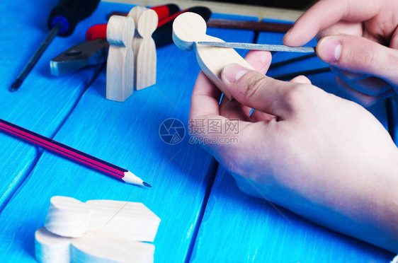 主人用手加工木材用工具在蓝色背景上工作创作由木头制成的国内工艺品人的小木图自己动手做概图片