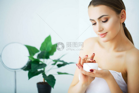 使用皮肤护理产品润湿剂或润滑剂以及照顾干肤色的美貌女图片