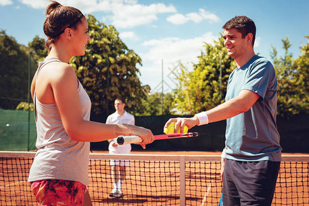 年轻夫妇在网球双人比赛前握着球和拍打图片
