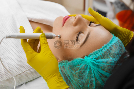 美容师使该设备成为美容院中一位美丽的年轻女子的微电流治疗程序美容和图片