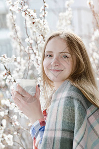 女孩拿着茶杯站在窗边微笑着容在背景中图片