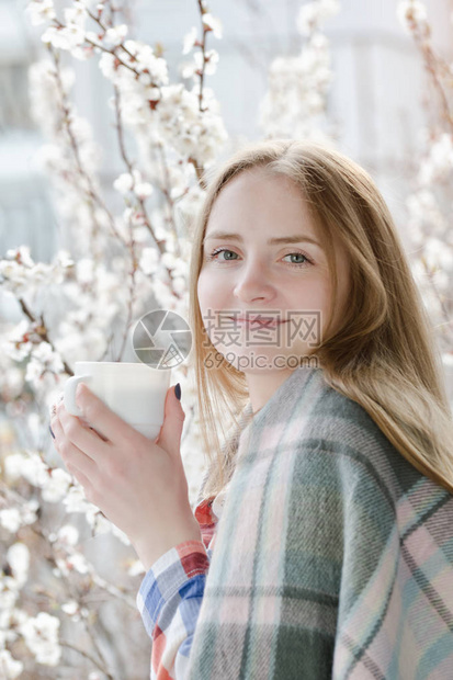 女孩拿着茶杯站在窗边微笑着容在背景中图片