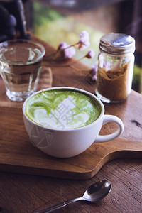 绿茶奶茶绿色茶热茶热喝拿铁白杯在咖啡店背景