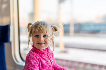 可爱的小女孩乘火车旅行孩子微笑着坐在火车上背景上宽明亮的阳光明媚的窗图片