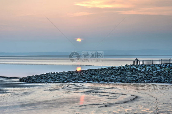 日落在英格兰莫雷坎贝湾的泥滩上由石图片