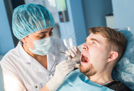 牙科手术期间坐在牙医椅子上的男人图片