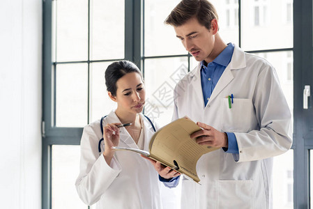 两位敬业的医生在现代医院内部一起检查患者病历中的信息图片
