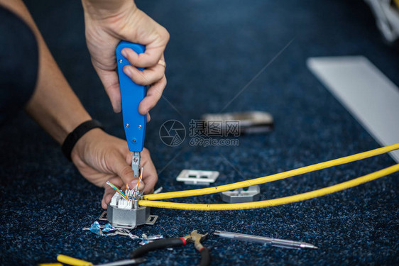 工人将网络电缆与RJ45插座连接起来图片