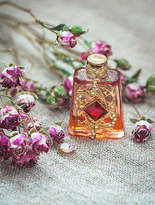 麻布背景上的干茶玫瑰和复古香水瓶图片