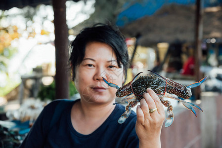 亚洲女人丰满的身体拿着新鲜的生海花蟹portunuspelagicus优质展示在背景图片