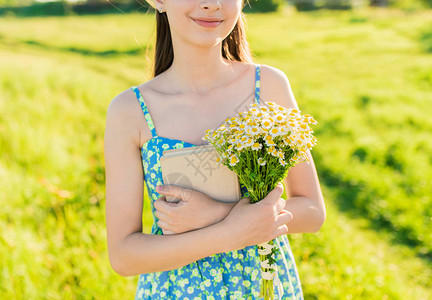 年轻的浪漫女孩拥抱着一束野花在多汁绿草的背景上夏图片