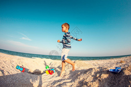 一个男孩正在沙滩上玩沙子孩子沿着海岸逆着天空奔跑孩子在大自然中玩得很开心这个图片