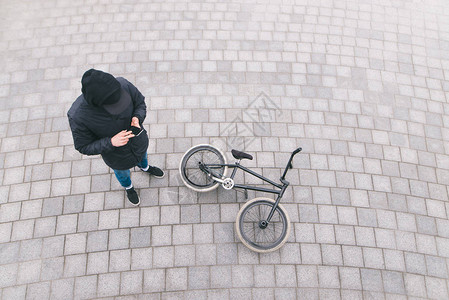 一名年轻人站在一辆BMX自行车附近的街上高清图片