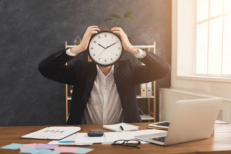 商人用时钟遮住脸在办公室戴手表的人画像时间管理和时间是最宝贵的资源概图片