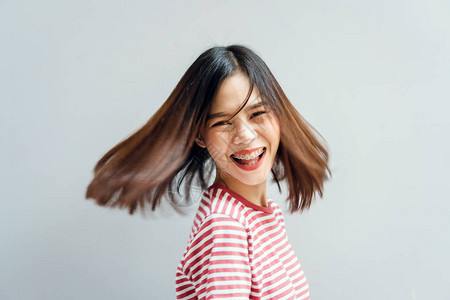 年轻女孩快乐的笑容和欢乐的穿着红色礼服在旋转部队周围挥舞着手势发图片