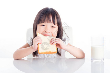 小亚洲女孩吃面包和一杯牛奶早餐图片