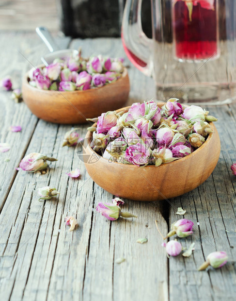 玫瑰茶叶卡德酒木板上木碗中的小干花芽图片