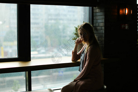 金发女孩坐在咖啡馆窗户旁边休息和图片