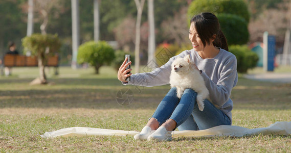 女人用手机和她的狗自拍图片