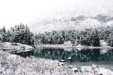 冬天湖的镜面有山脉的山上的第一场雪前往阿尔图片