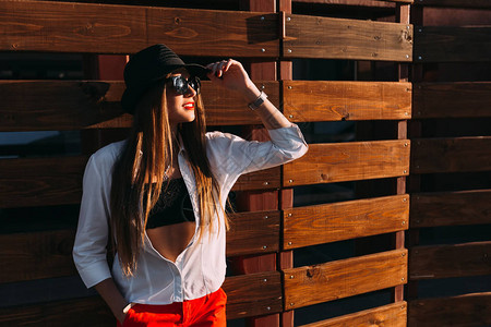 一个穿着时尚的衣服太阳镜和黑帽子的年轻女孩与时尚的形象相得益彰女孩图片